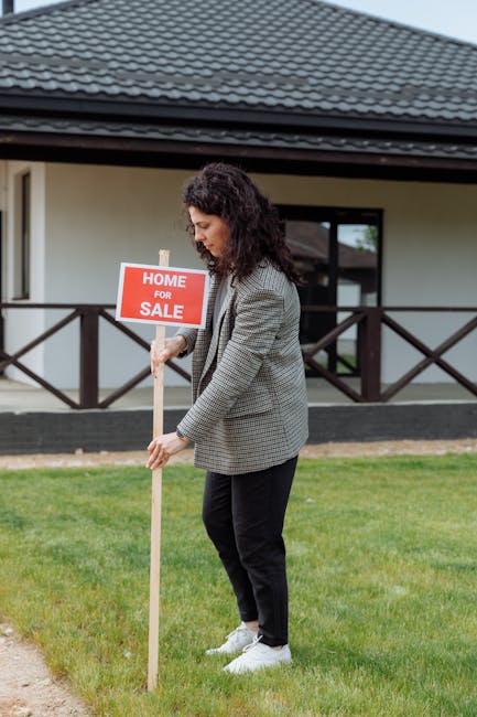 Woman placing a home for sale sign in front of a house, showcasing real estate career.