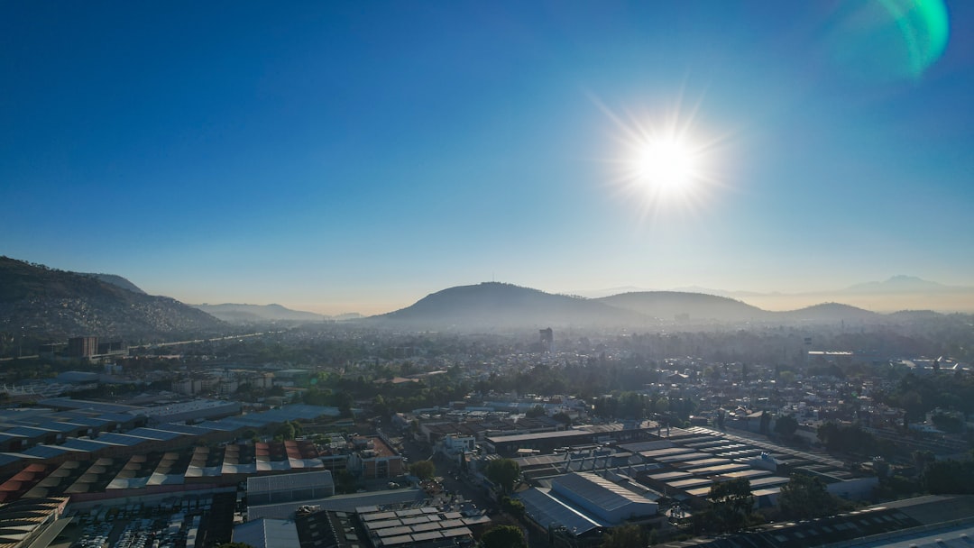 the sun is shining over a city with mountains in the background