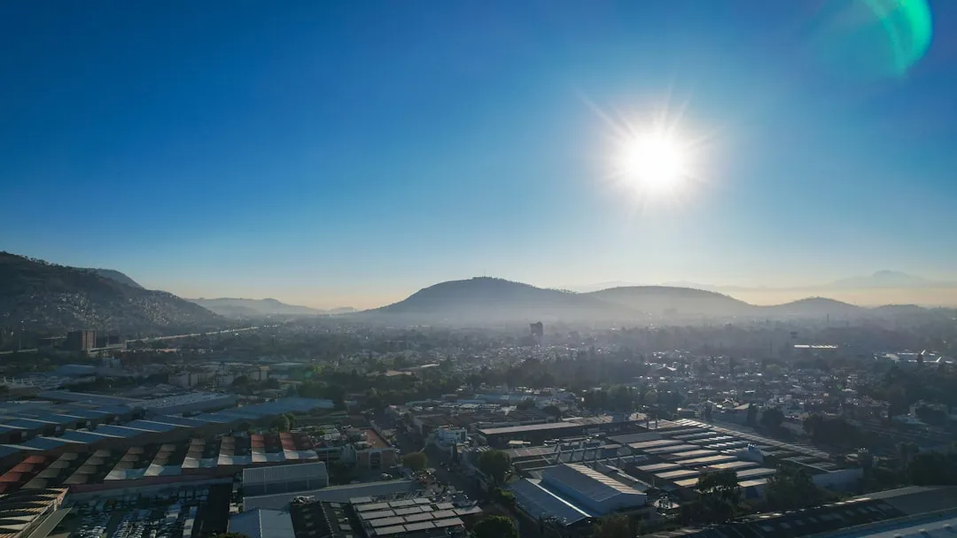 the sun is shining over a city with mountains in the background